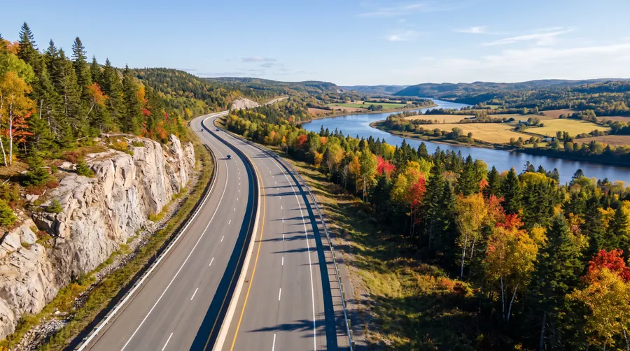 Autoroute le long d'une paroi de granit, collines boisées en automne
